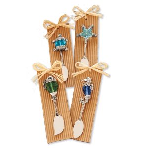 Four decorative cheese spreaders with sea-themed handles, each tied to a ribbed cardboard backing with a raffia bow.