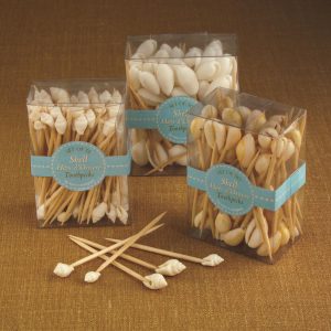 Three clear boxes of shell hors d’oeuvre toothpicks displayed on a brown surface, with several toothpicks lying in front.