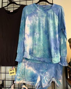 Blue and white tie-dye long-sleeve shirt and matching shorts on display next to a black shirt with a 30% off sign.