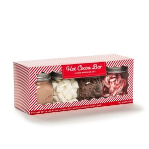 Four mason jars in a striped box containing hot cocoa mix, marshmallows, chocolate pieces, and candy canes.