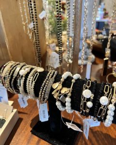 A display of assorted bracelets, including pearl and beaded styles, arranged on a black holder with price tags visible.