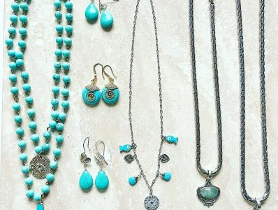 Assorted turquoise and silver jewelry, including necklaces, earrings, and a bracelet, displayed on a light surface.