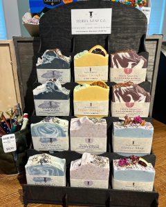 Display of Tierra Soap Co. handmade soaps in various colors and designs arranged on a black stand.