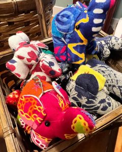 A basket filled with colorful, patterned fabric elephant keychains.