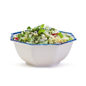 A white bowl with a blue rim filled with tabbouleh salad made of bulgur, herbs, cucumber, and tomato.