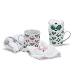 Two patterned mugs with pink and green designs, each paired with a white cloth embroidered with matching motifs.