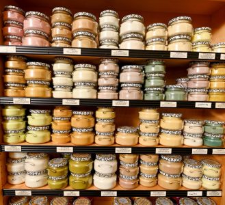 Shelves filled with stacked ceramic jars in various pastel colors, arranged in neat rows and columns.