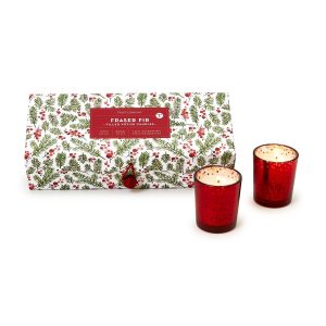 Box of Fraser Fir scented candles with festive holiday design and two lit red votive candles beside it.