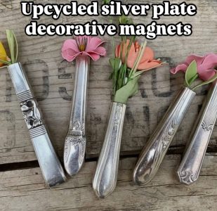Four upcycled silver plate utensil handles used as flower-shaped decorative magnets on a wooden surface.