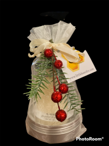 Gift-wrapped body spa set with festive red berries, green pine sprig, and a ribbon, labeled with a business card.