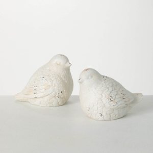 Two white ceramic bird figurines sit side by side on a plain light-colored surface against a white background.