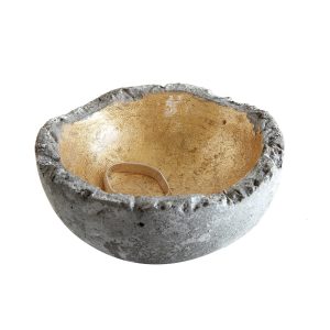 A rough-edged concrete bowl with a gold-painted interior, holding a single silver ring.