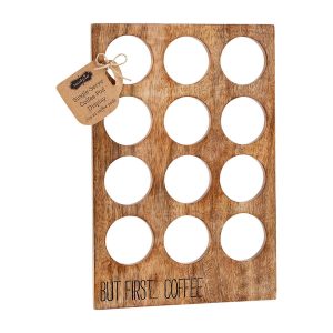 Wooden coffee pod holder with twelve circular slots and the phrase "BUT FIRST... COFFEE" engraved at the bottom.