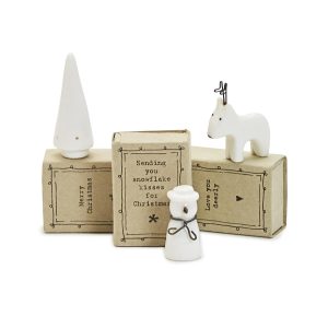 White ceramic Christmas figurines and three brown gift boxes with festive messages displayed on the front.