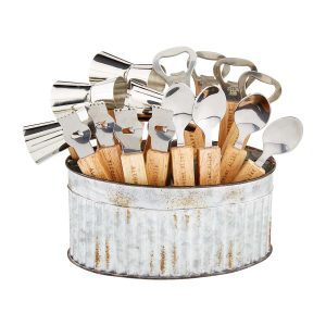A metal container holds wooden-handled bottle openers and metal measuring jiggers against a white background.