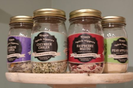 Four jars of Spirit Sippers drink mixes labeled Cucumber Cooler, Raspberry Mojito, Sunshyne Shine, and Pear Apple.