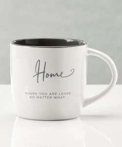 White ceramic mug with "Home" and the phrase "Where you are loved. No matter what." printed on the front in gray text.