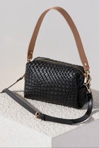 A black woven leather handbag with gold zipper and hardware, featuring a tan handle and detachable black shoulder strap.