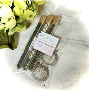 A 3-piece green tea kit with tea leaves in glass tubes and two tea infusers, packaged in a clear plastic bag.