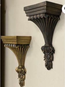 Two ornate, wall-mounted shelves with decorative, fluted designs in bronze and dark brown finishes.
