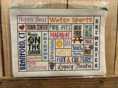 A canvas pouch featuring colorful text listing Branford, CT attractions and activities on a wooden background.