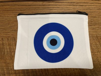 White zippered pouch with a blue and black concentric circle design on a wooden surface.