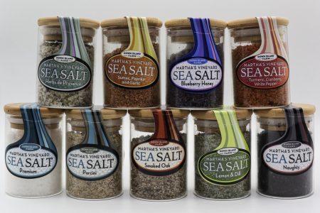 Ten glass jars of Martha’s Vineyard Sea Salt in various flavors are arranged in two rows against a white background.