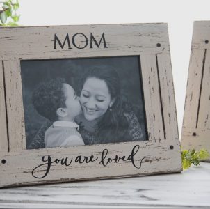 A framed photo labeled "MOM" shows a child kissing a smiling woman, with "you are loved" written on the frame.