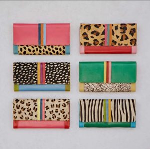 Six colorful wallets with animal print patterns are arranged in two rows on a neutral background.