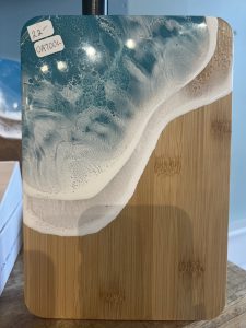 A small bamboo cutting board with blue and white resin art resembling ocean waves on one corner.
