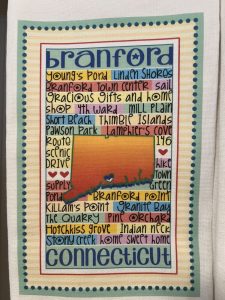 A colorful tea towel featuring a map of Branford, Connecticut with local landmarks and attractions listed inside the state outline.