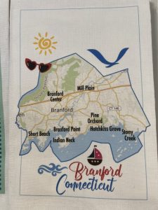 A stylized map of Branford, Connecticut, showing neighborhoods, a sun, sunglasses, bird, and sailboat graphics.