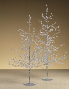 Two decorative silver wire trees with crystal-like beads stand on a neutral surface against a beige background.