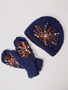 A navy knit hat and mittens with colorful embroidered and beaded starburst patterns on a white background.
