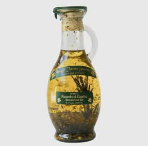 A glass bottle of Hongar Farms Gourmet Roasted Garlic Seasoned Oil with herbs visible inside the oil.