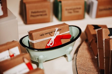 A small cardboard package labeled "ugly sweater weather" tied with string sits in a miniature bathtub display.