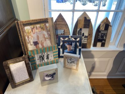 A collection of framed photos and a handwritten note displayed on a table by a window with snow visible outside.