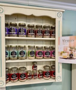A white wooden shelf displays jars of cocktail infusion mixes in various flavors, with a Vena's Fizz House menu beside it.