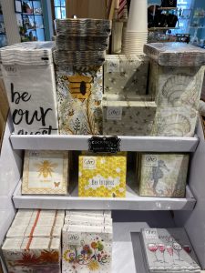 Display of decorative cocktail napkins with various designs, including bees, flowers, wine glasses, and inspirational quotes.