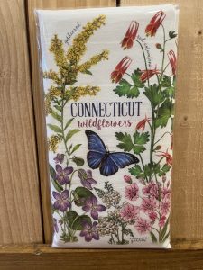 Tea towel with illustrations of Connecticut wildflowers and a blue butterfly against a wooden background.