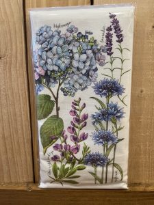A decorative napkin featuring illustrations of hydrangea, lavender, lupine, and cornflower against a wooden background.