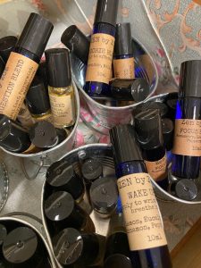 Small metal buckets filled with various essential oil roll-on bottles labeled with different blends and ingredients.