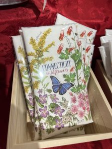 Packets labeled "Connecticut wildflowers" with colorful floral and butterfly illustrations displayed in a wooden box.