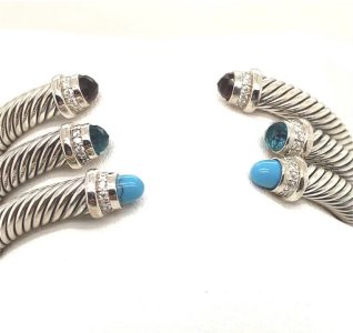 Two silver twisted cable bracelets with gemstone end caps, including blue, teal, and dark stones, displayed on a white background.
