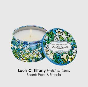 A scented candle in a floral-patterned tin labeled "Field of Lilies," with the lid beside it. Scent: Pear & Freesia.