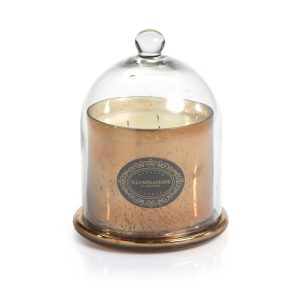 A gold candle with three wicks is covered by a clear glass cloche on a matching gold base.