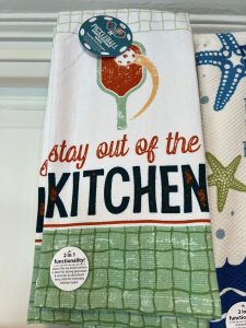 White kitchen towel with green grid pattern, chili pepper graphic, and text reading “stay out of the KITCHEN.”.