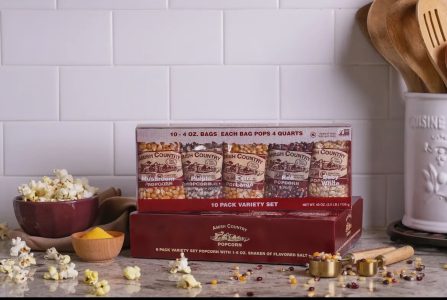 Assorted Amish Country popcorn kit on a kitchen counter with popped popcorn, seasonings, and utensils nearby.